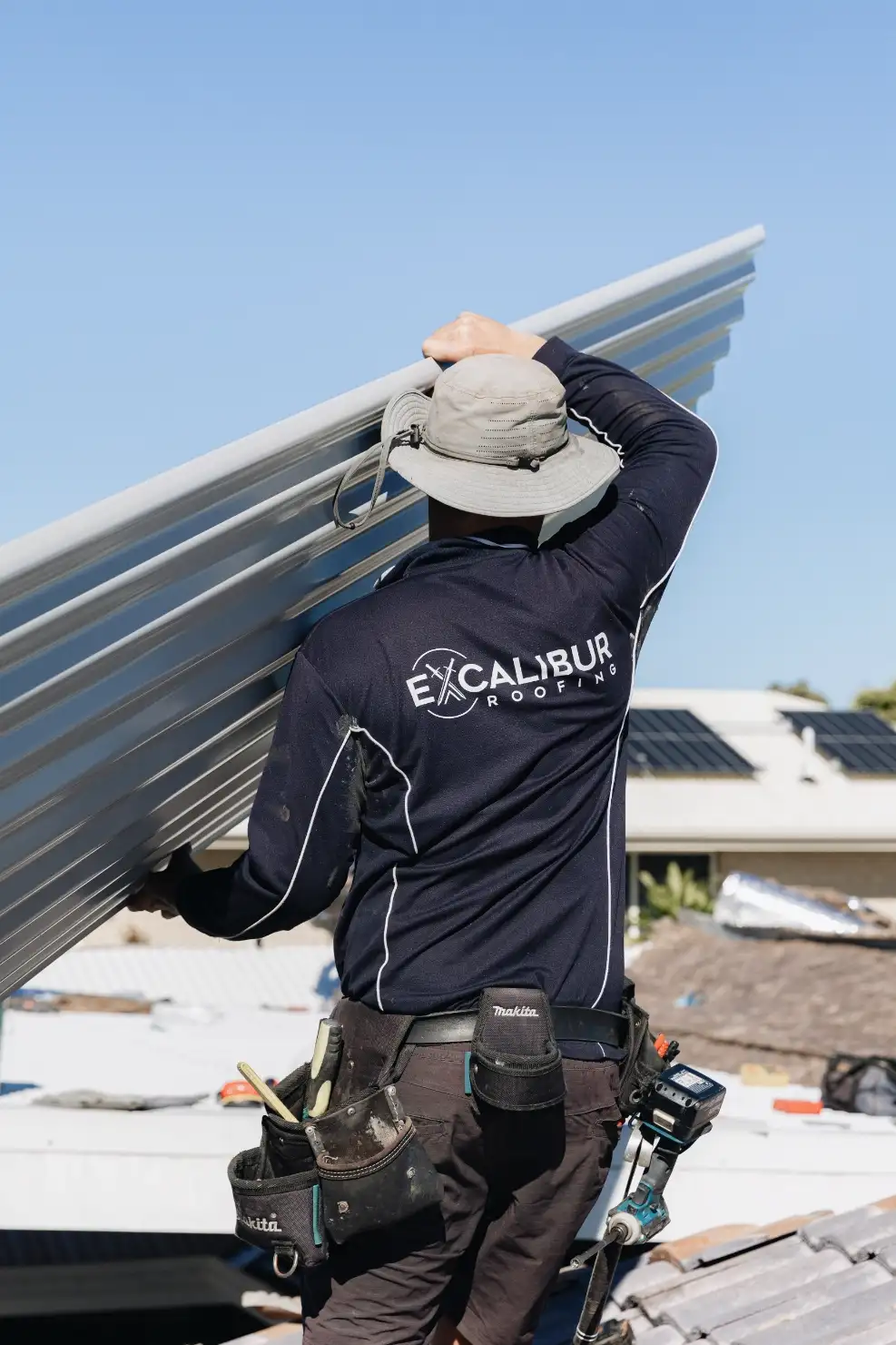 Professional roofer handling metal sheeting during a roof repair